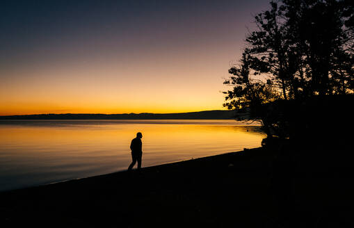 Silhouette Mann zu Fuß auf Seeufer gegen den Himmel bei Sonnenuntergang - EYF02090