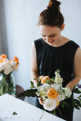 High Angle View Of Woman Arranging Flowers In Vase At Table - EYF02152