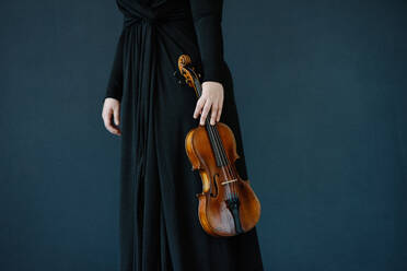 Midsection Of Woman Holding Violin Against Blue Background - EYF02153