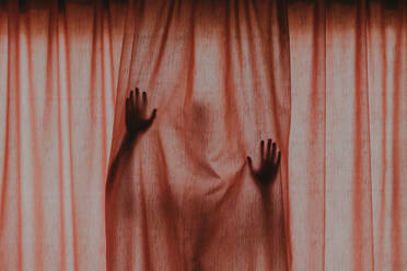 Person versteckt sich hinter braunem Vorhang - EYF02196