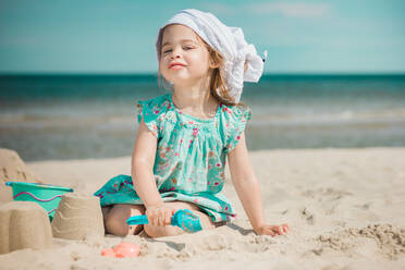 Portrait Of Girl Making Sandcastles While Sitting At Beach - EYF02234
