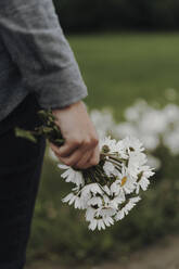 Mittelteil einer Frau, die Blumen hält - EYF02267