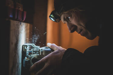 Close up of man wearing headlamp doing DIY. - CUF54928