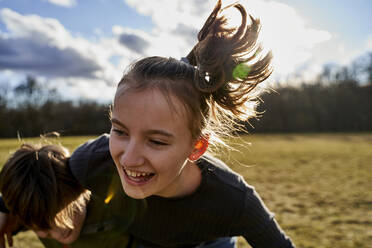 Carefree girl playing with brother on a meadow - AUF00273