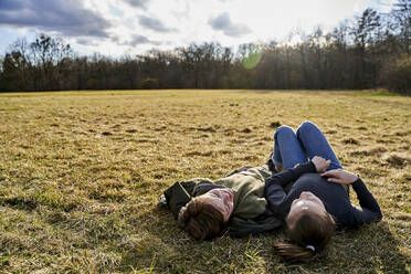 Brother and sister lying on a meadow - AUF00275