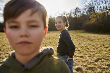 Bruder und Schwester auf einer Wiese - AUF00277