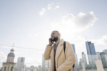 Stylish man on the phone on observation terrace with skycraper view, Frankfurt, Germany - AHSF02128