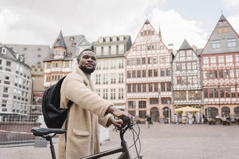 Portrait of stylish man with a bicycle in old town, Frankfurt, Germany - AHSF02147