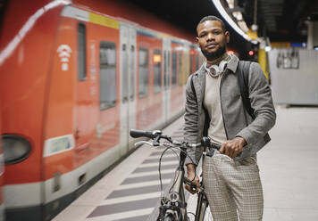 Stilvoller Mann mit Fahrrad und Kopfhörern in einer U-Bahn-Station - AHSF02161
