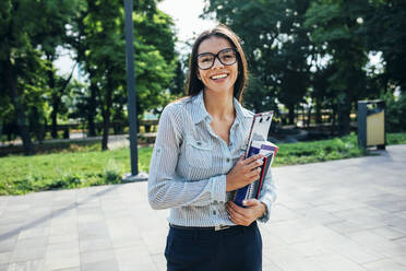 Lächelnde Studentin mit Büchern in einem Park - OYF00121