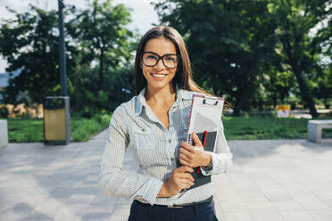 Smiling student with books in a park - OYF00122