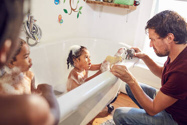 Vater und Tochter spielen in der Badewanne mit Spielzeugtieren - CAIF25481