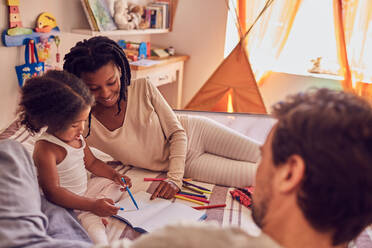 Junge Familie beim Malen auf dem Bett - CAIF25484