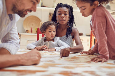 Junge Familie spielt Scrabble-Wortspiel am Tisch - CAIF25495