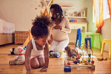 Pregnant mother and daughter playing with toys - CAIF25503