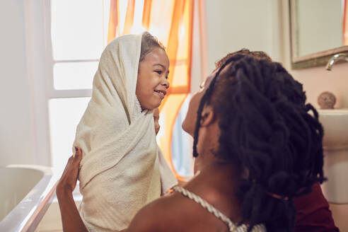 Glückliche Mutter trocknet ihre Tochter nach dem Bad mit einem Handtuch ab - CAIF25508