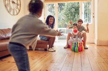 Junge Familie spielt Bowling im Wohnzimmer - CAIF25523