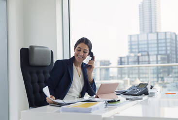 Smiling businesswoman talking on telephone in urban office - CAIF25573