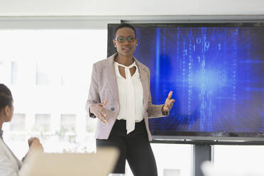 Geschäftsfrau am Fernsehschirm, die eine Sitzung im Konferenzraum leitet - CAIF25589