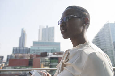 Ambitious, confident businesswoman on sunny, urban balcony - CAIF25653