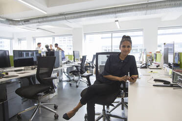 Portrait confident businesswoman in open plan office - CAIF25689