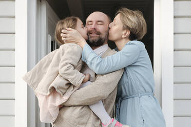 Glückliche Familie umarmt und küsst sich vor ihrem Haus - VYF00119