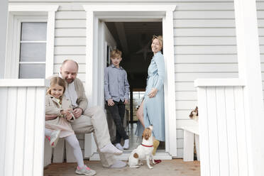 Glückliche Familie mit Katze und Hund auf der Veranda ihres Hauses - VYF00120
