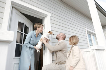 Glückliche Familie mit Hund auf der Veranda ihres Hauses - VYF00121