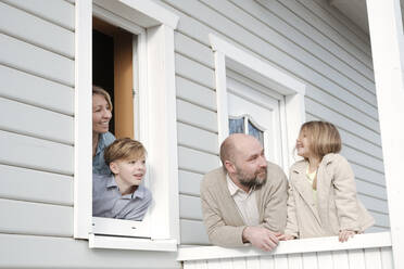Glückliche Familie auf der Veranda ihres Hauses - VYF00123