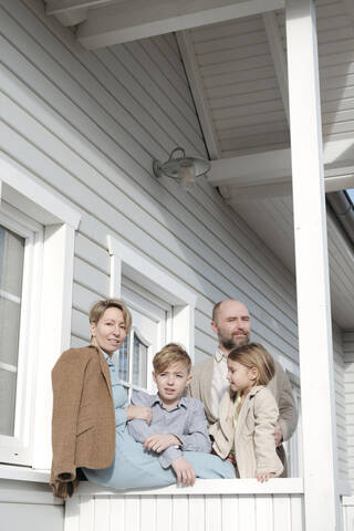 Porträt einer Familie auf der Veranda ihres Hauses, lizenzfreies Stockfoto