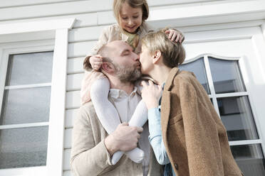 Glückliche Familie umarmt und küsst sich vor ihrem Haus - VYF00131
