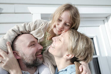 Happy family hugging in front of their house - VYF00133