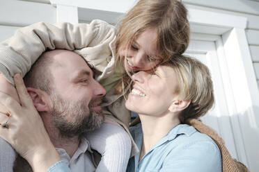 Happy family hugging in front of their house - VYF00134