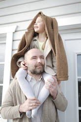 Portrait of father with happy daughter on his shoulders in front of their house - VYF00138