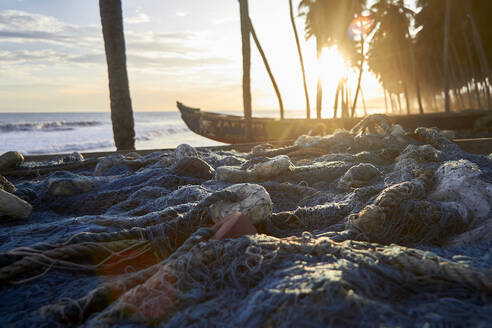 Ghana, Keta, Fischernetze vor Booten, die bei Sonnenuntergang am Strand liegen - VEGF01851