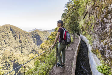 Portugal, Madeira, Ribeiro Frio, Weibliche Rucksacktouristin bewundert die umliegende Landschaft von einem Aussichtspunkt entlang der Levada do Furado - WDF05921