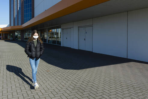 Girl with mask walking outside at closed shopping center - OJF00364