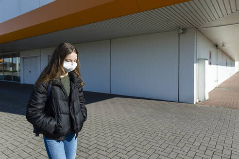 Girl with mask walking outside at closed shopping center - OJF00365