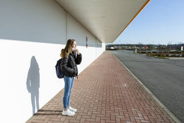 Mädchen mit Maske steht auf einer leeren Straße - OJF00367