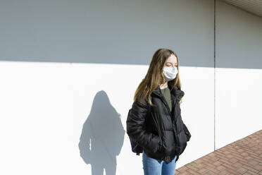 Mädchen mit Maske vor einer Wand stehend - OJF00368
