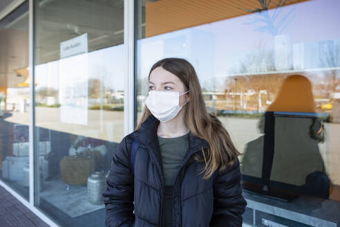 Girl with mask standing at closed shopping center - OJF00373