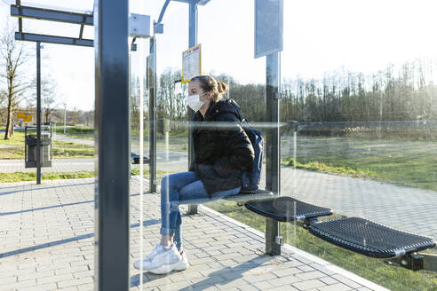 Portrait of a girl with mask waiting at bus stop - OJF00380