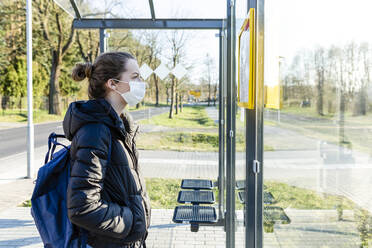 Porträt eines Mädchens mit Maske, das an der Bushaltestelle wartet - OJF00383