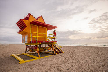 Frau in roter Badehose auf Rettungsschwimmerhütte am Miami Beach, Miami, Florida, USA - DAWF01274