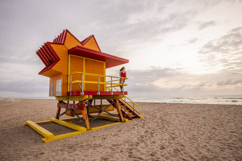 Frau in roter Badehose auf Rettungsschwimmerhütte am Miami Beach, Miami, Florida, USA - DAWF01274