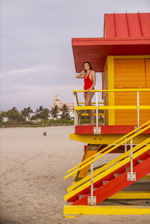 Frau in roter Badehose auf Rettungsschwimmerhütte am Miami Beach, Miami, Florida, USA - DAWF01279