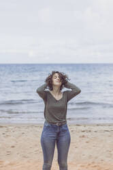 Junge Frau genießt den Wind am Strand - FVSF00011