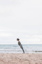 Junge Frau am Strand stehend, geneigt - FVSF00017