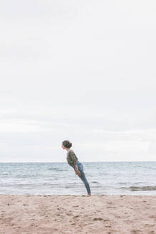 Junge Frau am Strand stehend, geneigt - FVSF00017