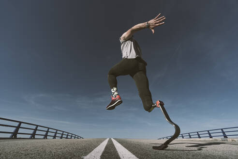 Disabled athlete with leg prosthesis exercising on a road - DAMF00315